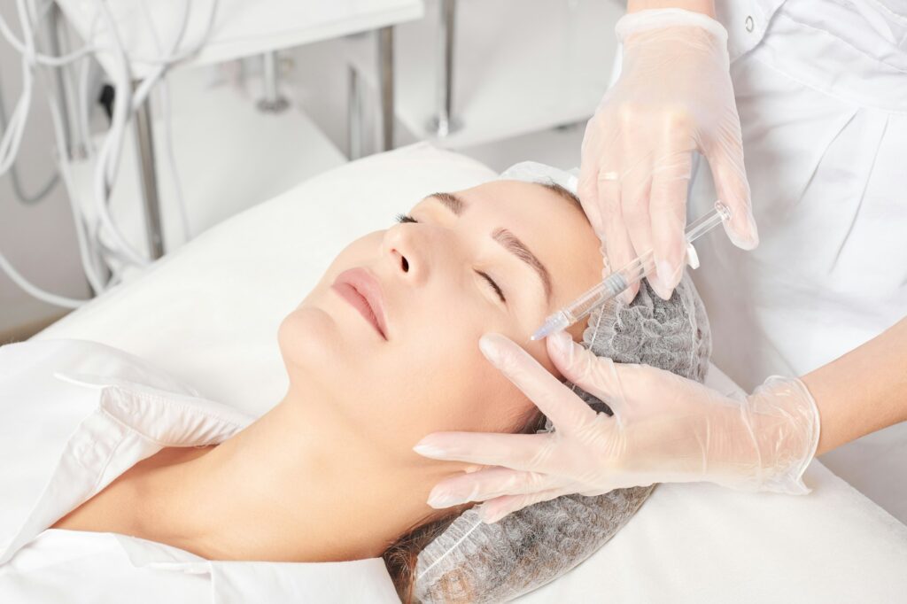 Cosmetologist makes rejuvenation injection in woman face, anti aging procedure in beauty salon